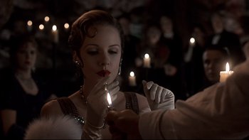 Movie still from “Addams Family Values” (1993), directed by Barry Sonnenfeld – A person lighting a candle on a woman's face; Close Up shot, Over the shoulder angle