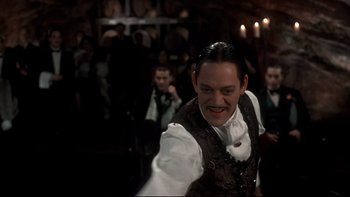 Movie still from “Addams Family Values” (1993), directed by Barry Sonnenfeld – A man in a white shirt and a brown vest; Medium shot, Low angle