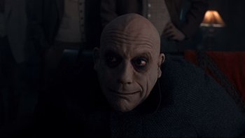 Movie still from “Addams Family Values” (1993), directed by Barry Sonnenfeld – A man with a bald head wearing headphones; Close Up shot, Over the shoulder angle