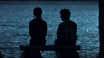 Movie still from “Addams Family Values” (1993), directed by Barry Sonnenfeld – Two people sitting on a bench near the water at night; Wide shot, Over the shoulder angle