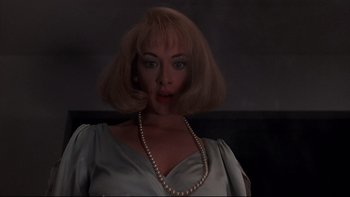 Movie still from “Addams Family Values” (1993), directed by Barry Sonnenfeld – A woman in a silver dress and a pearl necklace; Close Up shot, Low angle