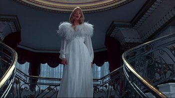 Movie still from “Addams Family Values” (1993), directed by Barry Sonnenfeld – A woman in a white dress standing on a staircase; Medium shot, Low angle