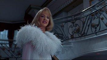 Movie still from “Addams Family Values” (1993), directed by Barry Sonnenfeld – A woman with blonde hair wearing a white feather boa; Medium shot, Low angle