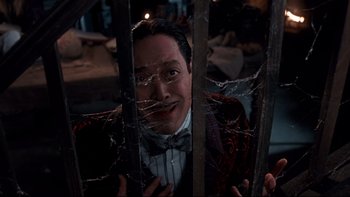 Movie still from “Addams Family Values” (1993), directed by Barry Sonnenfeld – A man in a bow tie is behind bars; Close Up shot, High angle