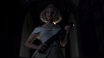 Movie still from “Addams Family Values” (1993), directed by Barry Sonnenfeld – A woman holding a gun in a dark room; Medium shot, Low angle