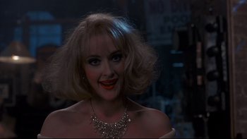 Movie still from “Addams Family Values” (1993), directed by Barry Sonnenfeld – A woman wearing a necklace and a red lipstick looks at the camera; Close Up shot, Over the shoulder angle