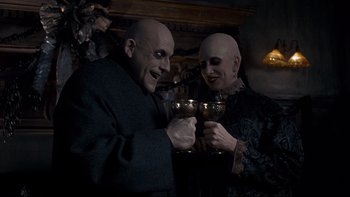 Movie still from “Addams Family Values” (1993), directed by Barry Sonnenfeld – A man and a woman holding a wine glass; Medium shot, High angle