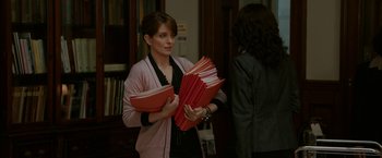 Movie still from “Admission” (2013), directed by Paul Weitz – A woman is holding a bunch of red folders; Medium shot, Over the shoulder angle