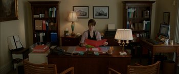 Movie still from “Admission” (2013), directed by Paul Weitz – A woman sitting at a desk holding a red folder; Medium shot, High angle