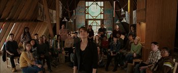 Movie still from “Admission” (2013), directed by Paul Weitz – A woman standing in front of a group of people in a room; Wide shot, Over the shoulder angle