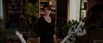 Movie still from “Admission” (2013), directed by Paul Weitz – A woman standing in a room next to a bicycle; Medium shot, Over the shoulder angle