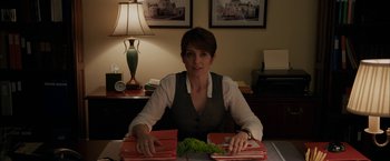 Movie still from “Admission” (2013), directed by Paul Weitz – A woman sitting at a desk with a bunch of folders; Medium shot, Over the shoulder angle