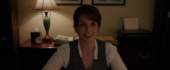 Movie still from “Admission” (2013), directed by Paul Weitz – A woman sitting at a desk in front of a lamp; Close Up shot, Over the shoulder angle