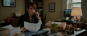 Movie still from “Admission” (2013), directed by Paul Weitz – A woman sitting at a table talking on the phone; Medium shot, Over the shoulder angle
