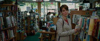 Movie still from “Admission” (2013), directed by Paul Weitz – A woman standing in front of a bookcase in a library; Medium shot, Over the shoulder angle