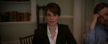 Movie still from “Admission” (2013), directed by Paul Weitz – A woman wearing a suit sitting at a table; Close Up shot, Over the shoulder angle