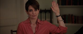 Movie still from “Admission” (2013), directed by Paul Weitz – A woman in a red shirt raising her right hand; Close Up shot, Low angle