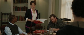 Movie still from “Admission” (2013), directed by Paul Weitz – A woman standing in front of a man at a dinner table; Medium shot, Over the shoulder angle
