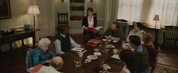 Movie still from “Admission” (2013), directed by Paul Weitz – A group of people sitting around a table with plates of food on top of it; Medium shot, Over the shoulder angle