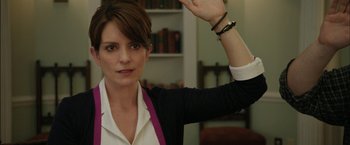Movie still from “Admission” (2013), directed by Paul Weitz – A woman in a white shirt and a black jacket holding her hand up; Close Up shot, Over the shoulder angle