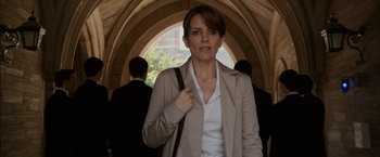 Movie still from “Admission” (2013), directed by Paul Weitz – A woman in a tan jacket holding a purse; Medium shot, Over the shoulder angle
