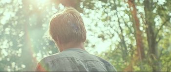 Movie still from “Adoration” (2019), directed by Fabrice du Welz – A man with blonde hair is looking out at the trees; Close Up shot, Over the shoulder angle