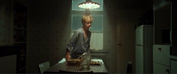 Movie still from “Adoration” (2019), directed by Fabrice du Welz – A man standing at a table with food on it; Medium shot, Low angle