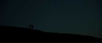 Movie still from “Adoration” (2019), directed by Fabrice du Welz – A couple of people standing on top of a hill at night; Extreme Wide shot, Low angle