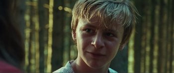 Movie still from “Adoration” (2019), directed by Fabrice du Welz – A young boy's face in the woods; Close Up shot, Low angle