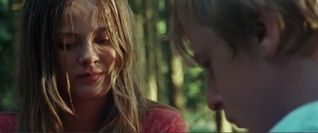 Movie still from “Adoration” (2019), directed by Fabrice du Welz – A man and a woman sitting next to each other in a forest; Close Up shot, Over the shoulder angle