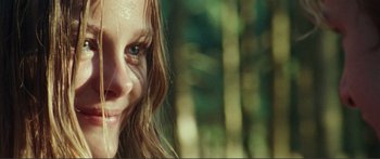 Movie still from “Adoration” (2019), directed by Fabrice du Welz – A woman's face in a forest; Close Up shot, Over the shoulder angle