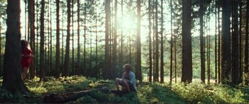 Movie still from “Adoration” (2019), directed by Fabrice du Welz – A man sitting on a tree stump in the middle of a forest; Wide shot, Low angle