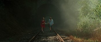 Movie still from “Adoration” (2019), directed by Fabrice du Welz – A man and a woman walking on a train track; Wide shot, High angle