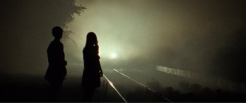 Movie still from “Adoration” (2019), directed by Fabrice du Welz – A woman standing on the side of a train tracks; Wide shot, Low angle
