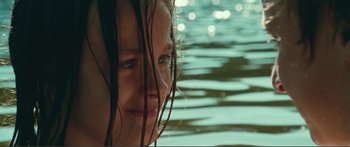 Movie still from “Adoration” (2019), directed by Fabrice du Welz – A woman with wet hair standing next to a body of water; Extreme Close Up shot, Low angle