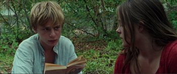 Movie still from “Adoration” (2019), directed by Fabrice du Welz – Two people sitting in the woods reading a book; Close Up shot, Over the shoulder angle