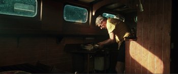 Movie still from “Adoration” (2019), directed by Fabrice du Welz – A man standing in front of an oven in a kitchen; Wide shot, High angle