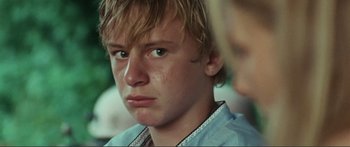Movie still from “Adoration” (2019), directed by Fabrice du Welz – A young person with a serious look on his face; Close Up shot, Over the shoulder angle