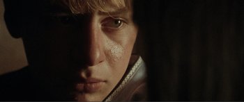 Movie still from “Adoration” (2019), directed by Fabrice du Welz – A young man's face in the dark; Extreme Close Up shot, Over the shoulder angle