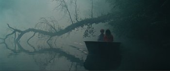 Movie still from “Adoration” (2019), directed by Fabrice du Welz – Two people sitting on a boat in the middle of a river; Wide shot, High angle