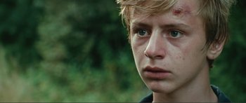 Movie still from “Adoration” (2019), directed by Fabrice du Welz – A young person's face with trees in the background; Close Up shot, Over the shoulder angle