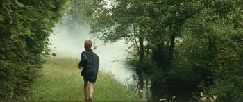 Movie still from “Adoration” (2019), directed by Fabrice du Welz – A young boy standing next to a body of water; Wide shot, High angle