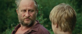 Movie still from “Adoration” (2019), directed by Fabrice du Welz – An older man and a young boy are talking to each other; Close Up shot, Over the shoulder angle