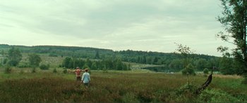 Movie still from “Adoration” (2019), directed by Fabrice du Welz – Two people are standing in a field near a lake; Extreme Wide shot, Low angle