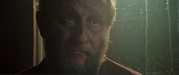 Movie still from “Adoration” (2019), directed by Fabrice du Welz – A person with a beard looking at the camera; Close Up shot, Low angle