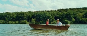 Movie still from “Adoration” (2019), directed by Fabrice du Welz – A man and a woman in a boat on a lake; Wide shot, High angle