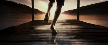 Movie still from “Adrift” (2018), directed by Baltasar Kormákur – A person walking on a dock with the sun setting in the background; Wide shot, Low angle