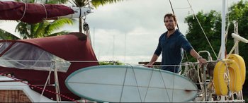 Movie still from “Adrift” (2018), directed by Baltasar Kormákur – A man standing next to a surfboard on the side of a boat; Medium shot, Low angle