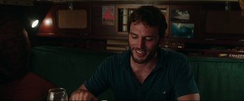 Movie still from “Adrift” (2018), directed by Baltasar Kormákur – A man sitting at a table with a book in front of him; Medium shot, Over the shoulder angle