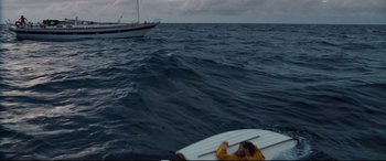 Movie still from “Adrift” (2018), directed by Baltasar Kormákur – A man on a surfboard in front of a boat in the ocean; Wide shot, High angle